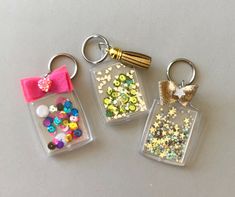 three keychains with different colored beads and bows on them, one has a pink bow