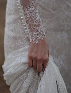 a close up of a person wearing a white dress and holding a bag with pearls on it