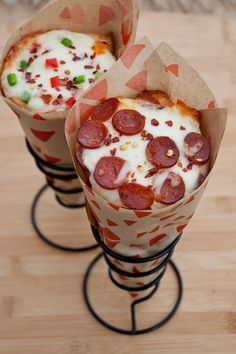 two pepperoni pizzas wrapped in paper sitting on top of a wooden table next to each other