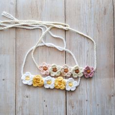 crocheted flower headbands on wooden surface with white string and brown beads