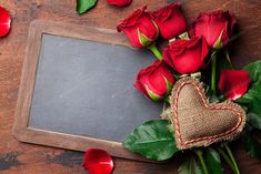 red roses and a heart on a wooden table with a chalkboard in the shape of a heart