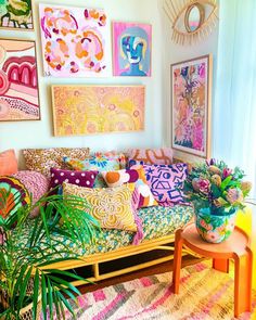 a living room filled with lots of colorful pillows and art on the wall above it