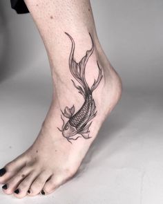 a woman's foot with a fish tattoo on it