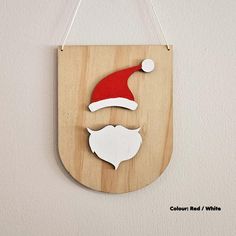 a wooden sign with a santa hat and beard hanging from the side on a wall