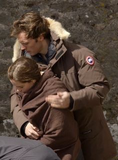 a man and woman walking down the street with one holding his arm around another person's shoulder