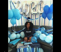 a woman sitting on a couch surrounded by balloons