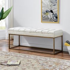 a white bench sitting on top of a hard wood floor next to a plant in a living room