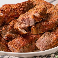 a white bowl filled with meat and seasoning on top of a striped table cloth