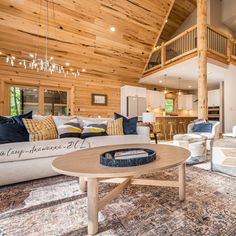 a living room filled with furniture and a chandelier hanging from the wooden ceiling