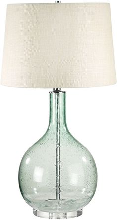 a glass table lamp with a white shade on the base and a light bulb attached to it