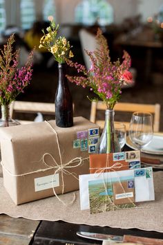 two vases filled with flowers sitting on top of a table covered in brown paper