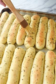 a pan full of bread rolls with a wooden spatula in the middle and sprinkled with seasoning