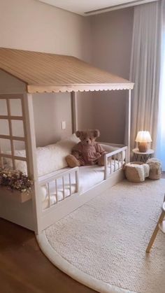 a teddy bear sitting on top of a bed in a room with white walls and wooden floors