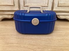 a blue lunch box sitting on top of a wooden floor next to a white dresser