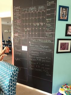 a chalkboard in the corner of a room with pictures on it and a baby's name written on it