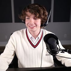 a young man wearing headphones sitting in front of a microphone