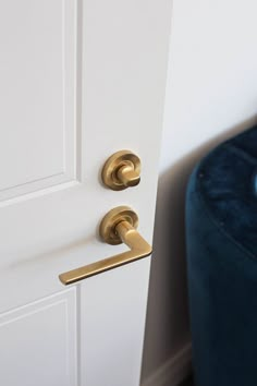 a close up of a door handle with a blue chair in the corner behind it