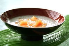 a bowl filled with milk and carrots on top of a leafy green surface