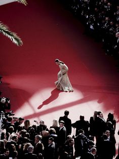 a woman walking down a red carpet in front of a large group of people onlookers