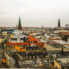 an aerial view of a city with tall buildings and green spires in the background