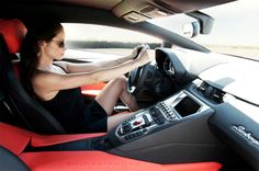 a woman sitting in the driver's seat of a sports car with her hands on the steering wheel