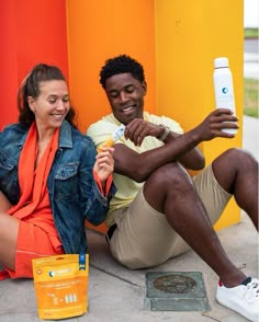 a man and woman sitting on the ground with toothpaste