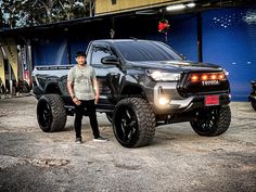 a man standing next to a black toyota truck