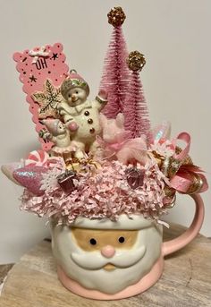 a pink christmas mug with teddy bears and other decorations on the top is sitting on a table