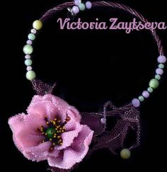 a pink flower is on a string with beads and beaded necklaces around it