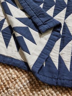 a blue and white quilt laying on top of a rug