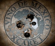 three people sitting on the floor in front of a sign that says no de mex