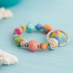 a close up of a bracelet on a bed with shells and starfishs in the background