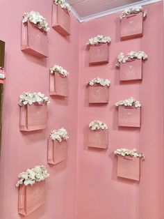 there are many pink boxes on the wall with white flowers in them and one is empty