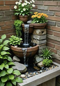 a water fountain surrounded by potted plants and rocks in front of a brick wall