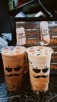 two iced drinks with mustaches on them sitting next to a sign that says kaba - van