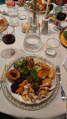 a dinner plate with many different types of food on it and wine glasses in the background