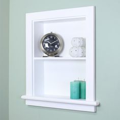 a white shelf with a clock and candles on it