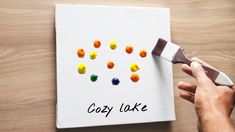 someone is painting the words cozy lake on a piece of paper with candy in it