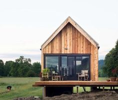 two small wooden houses sitting on top of a lush green field next to each other