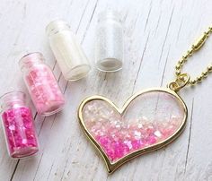 three small jars with pink and white sprinkles in them on a wooden surface