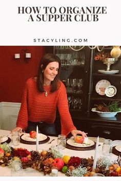 a woman in an orange sweater is setting a table with plates and fruit on it