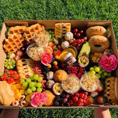 a box filled with lots of different types of food on top of green grass next to flowers