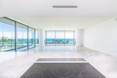 an empty living room with large windows overlooking the ocean