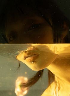 the reflection of a woman's face is seen through a glass window as she holds her hand up in front of her face