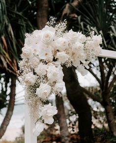 a wedding arch decorated with white flowers and baby's breath for an outdoor ceremony