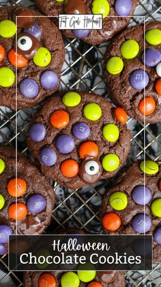 halloween chocolate cookies with candy eyes and m & m candies in the middle on a cooling rack