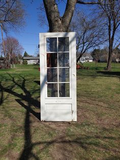 an old window sitting in the grass next to a tree