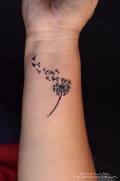 a woman's wrist with a dandelion tattoo on the left side of her arm