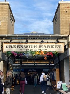 people are walking through the entrance to greenwich market, where there is an open air market