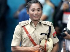 a woman in uniform walking down the street with other people behind her and cameras around her